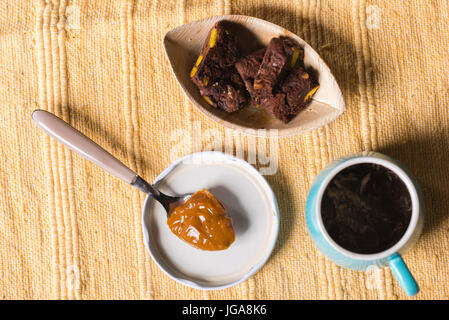 Dulce de Leche in einem Löffel, sehr süßen Crème Caramel oder Praline Creme aus Argentinien, schwarzen Kaffee Cand einige Schokoladenkekse. Stockfoto