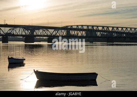 Silhouette der Brücke und Booten über den Fluss Santa Lucia bei Sonnenuntergang in Uruguay Stockfoto