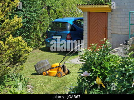 Defekte alte elektrische Rasenmäher Lüge auf dem grünen Garten Rasen. Sonnige Sommer ärmlichen Hof Tag Landschaft Stockfoto