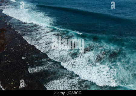 Meer mit riesigen Wellen und schwarzen Sandstrand in Bali, Indonesien. Stockfoto