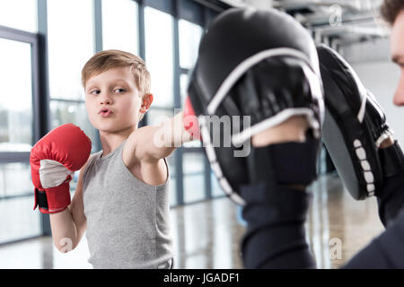 junge Boxer üben Schläge mit Trainer Stockfoto