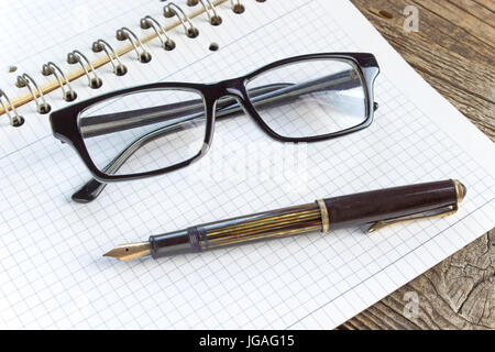 Füllfederhalter und Spiral-Notizbuch mit Brille Stockfoto