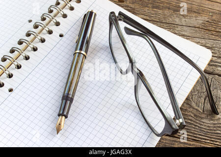 Füllfederhalter und Spiral-Notizbuch mit Brille Stockfoto