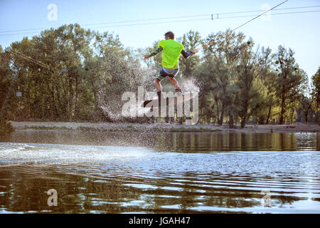 Man beschäftigt sich mit Extremsport, springt er auf dem Brett auf dem Wasser. Stockfoto