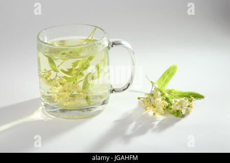 Kalk-Tee in eine Glasschale und Blütenstand von Linden. Stockfoto