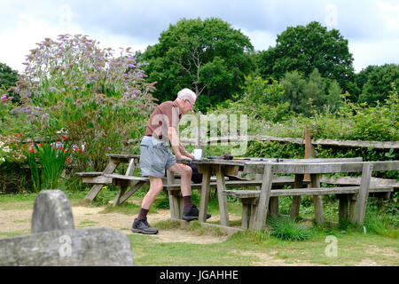 Sussex, UK. Einsame ältere männliche Wanderer rund um für eine Rast an Picknick-Tisch sitzen. Stockfoto