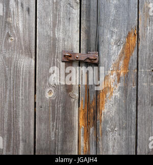 Rostige kleine eiserne Riegel auf einem modernden große Holztür. Vintage-Stil-Hintergrund Stockfoto