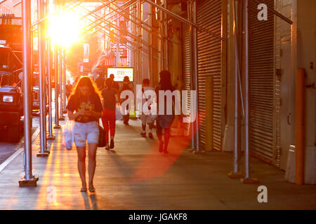 Eine Person geht ein New York City Straße an einem warmen Sommertag mit dem Diesigen Nachmittag Sonne drohenden niedrig und großen im Hintergrund. Stockfoto