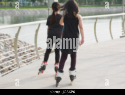Verschwommene Jugendlichen Rollschuhe im Park im Freien zu spielen. Teenager-Mädchen auf Rollschuhen im Freien. Stockfoto
