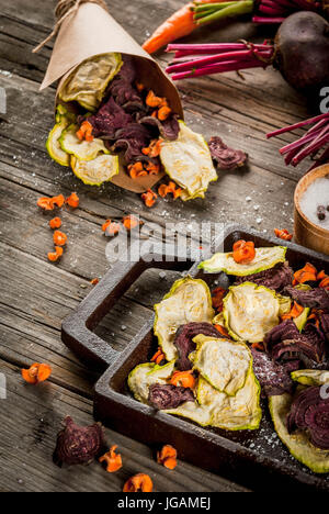 Bio-Ernährung essen. Die vegane Ernährung. Getrocknetes Gemüse. Hausgemachte Chips aus Rüben, Karotten und Zucchini. Auf alten rustikalen Holztisch mit frischem Gemüse Stockfoto