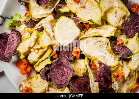 Bio-Ernährung essen. Die vegane Ernährung. Getrocknetes Gemüse. Home-Chips aus Rüben, Karotten und Zucchini. Auf einem weißen Marmortisch mit frischem Gemüse. Clos Stockfoto