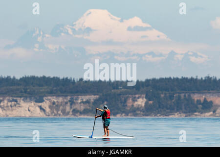 Paddle boarding am Puget Sound mit Mount Baker im Hintergrund stand. Stockfoto