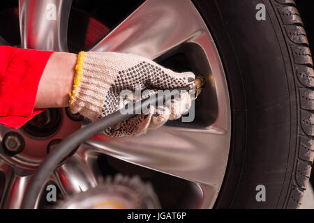 Nahaufnahme eines Mechanikers Hand prüfen den Luftdruck eines Reifens in Auto-Reparatur-service Stockfoto