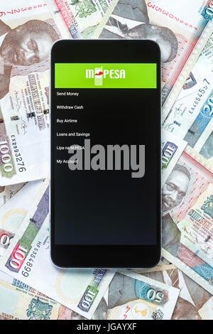 Safaricom M-Pesa fintech Mikrofinanz geld Transaction Service am Telefon mit kenianischen Schilling Banknoten Hintergrund Stockfoto