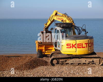 Eine kleine gelbe verfolgt Kettenbagger arbeiten an einem Strand Kies, UK zu bewegen. Stockfoto