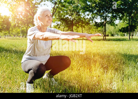 Positiv im Alter Frau hockt im Park zu tun Stockfoto