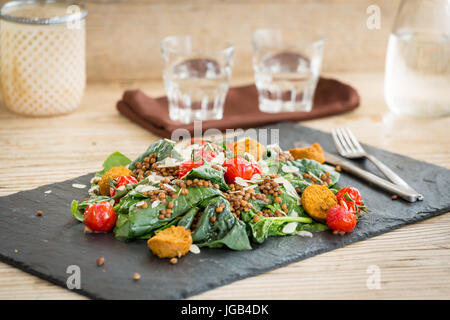 Köstlicher Salat mit gebackenen Tomaten, Falafels und Linsen auf Steinplatte serviert Stockfoto