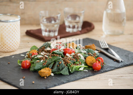 Köstlicher Salat mit gebackenen Tomaten, Falafels und Linsen auf Steinplatte serviert Stockfoto