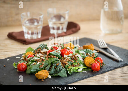 Köstlicher Salat mit gebackenen Tomaten, Falafels und Linsen auf Steinplatte serviert Stockfoto