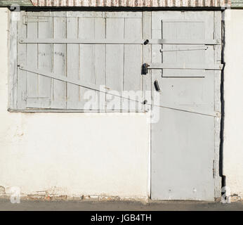 Fototextur der alten Holztüren und Fenstern mit Metall-Einsätze und eine aufklappbare Scheune-Sperre. Die Türen und Fenster sind grau lackiert. Stockfoto