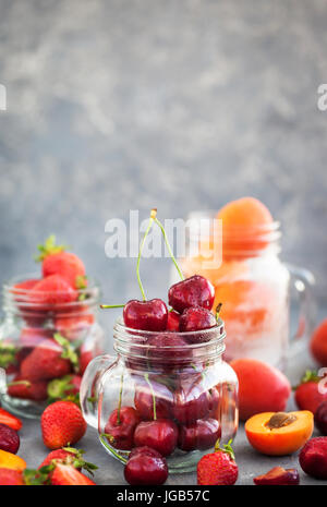 Frische reife Sommer Kirsche, Erdbeere und Aprikosen im Glas Einweckgläser Stockfoto