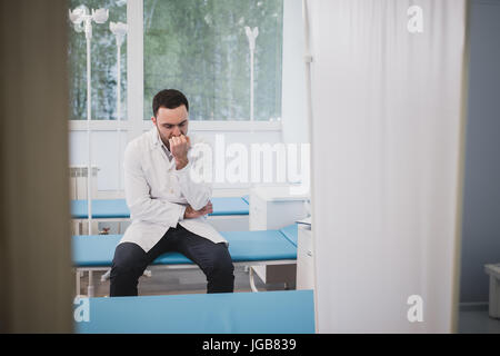 Müde Arzt allein im Krankenhaus sitzen. Stockfoto