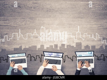 Gruppe von drei Personen mit Geräten in Händen arbeiten zusammen als Symbol der Vernetzung und Kommunikation Stockfoto