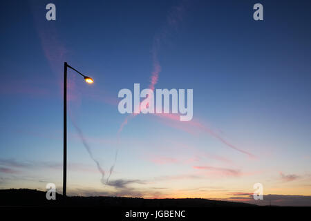 Straßenlaterne & Jet Trails bei Dämmerung, Whitehead, Nordirland. Stockfoto