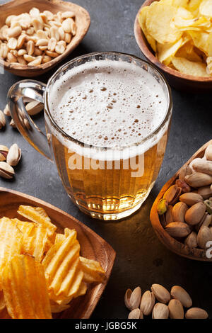 Lager-Bierkrug und Snacks am Steintisch. Muttern, chips Stockfoto