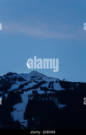 Der Mondaufgang über Blackcomb Peak in der Morgendämmerung. In Whistler, Kanada aufgenommen. Stockfoto