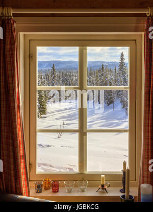 Durch eine alte quadratische Fenster schaut. Draußen ist Schnee und sonniges Wetter, eine Winterlandschaft. Stockfoto