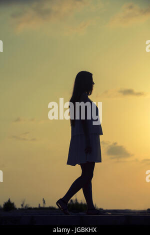 Voller Länge Silhouette einer Frau zu Fuß im Freien bei Sonnenuntergang Stockfoto