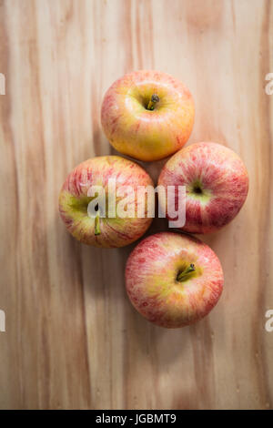 Vier Äpfel auf einer Holzfläche.  Pink Lady-Vielfalt Stockfoto