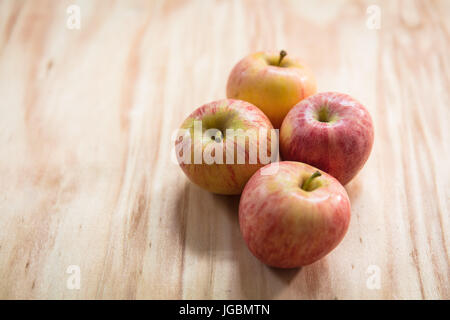 Vier Äpfel auf einer Holzfläche.  Pink Lady-Vielfalt Stockfoto