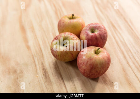 Vier Äpfel auf einer Holzfläche.  Pink Lady-Vielfalt Stockfoto