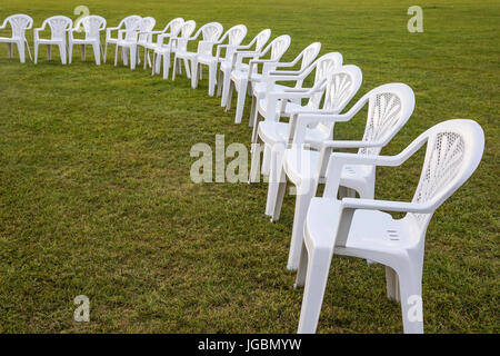 Weiße Plastikstühle auf einer Wiese in einem Kreis für Meditation angeordnet. Stockfoto