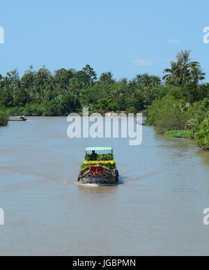 Menschen steuern Frachtboot auf dem Mekong River am sonnigen Tag im Mekong-Delta, Südvietnam. Stockfoto