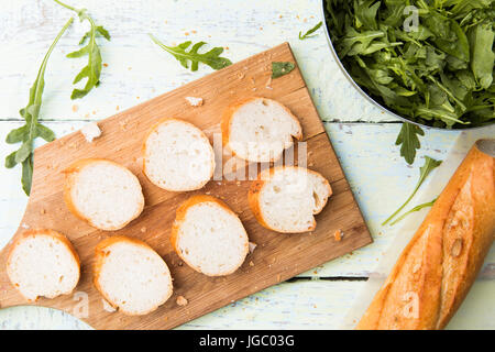 Foto von geschnitten Brot, Greens auf Holztisch Stockfoto