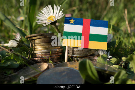 Zentralafrikanische Republik Flagge mit Stapel von Geld Münzen mit Rasen und Blumen Stockfoto