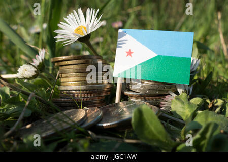 Dschibuti-Fahne mit Stapel von Geld Münzen mit Rasen und Blumen Stockfoto