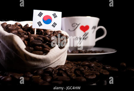 Südkoreanische Flagge in einer Tasche mit Kaffeebohnen auf schwarzem Hintergrund isoliert Stockfoto