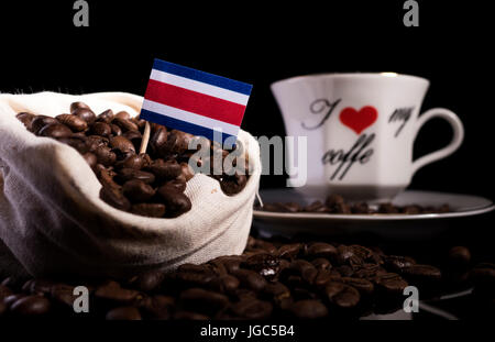 Costa Rica Flagge in einer Tasche mit Kaffeebohnen auf schwarzem Hintergrund isoliert Stockfoto