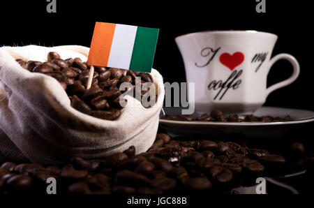 Elfenbeinküste-Flagge in einer Tasche mit Kaffeebohnen auf schwarzem Hintergrund isoliert Stockfoto