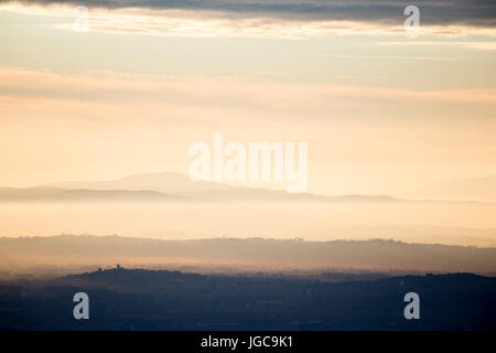 Verschiedenen Schichten der Berge und Hügel in der Mitte ein goldener, orange Licht bei Sonnenuntergang mit Wolken auch reflektiert Licht und Städte skylines Stockfoto