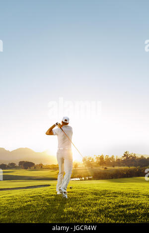 Rückansicht der Golfer schlagen Fahrer auf einem Golfplatz in der Sonne. Voller Länge Schuss des jungen Mannes an einem sonnigen Tag Golf spielen. Stockfoto