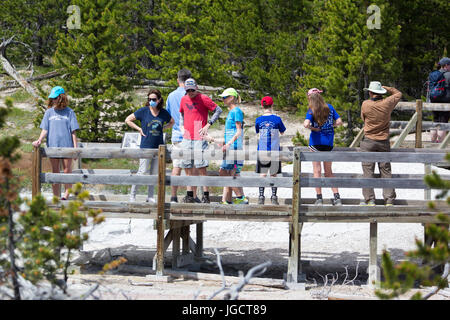 Touristen auf der Promenade am Künstler Paintpots im Yellowstone National Park. Eine Frau trägt eine Mund-Kappe gegen den Geruch von Schwefel Stockfoto