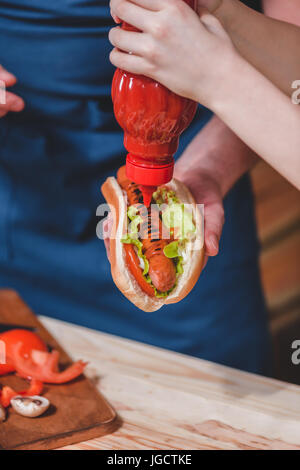 Close-up Teilansicht von Vater und Sohn mit Ketchup vorbereiten, hot Dog, Vater und Sohn Kochen Konzept Stockfoto