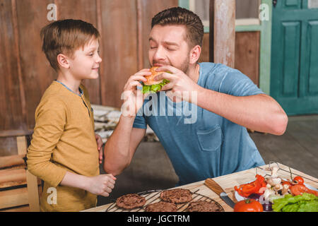 Seitenansicht des Menschen hausgemachte Burger mit kleinen Sohn in der Nähe von Essen Stockfoto