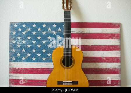 Gitarre, lehnte sich gegen eine amerikanische Flagge auf Holz gemalt Stockfoto