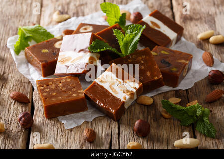 Quadratische Süßigkeiten Toffee mit Nüssen verziert mit Minze Closeup auf einem Tisch. horizontale Stockfoto